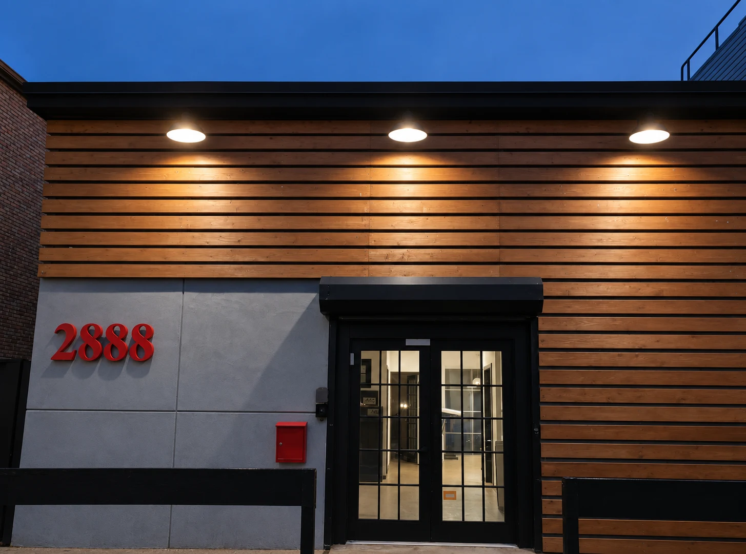 2888 Gerritsen Avenue: Wood-clad facade with an illuminated entrance and red address numerals