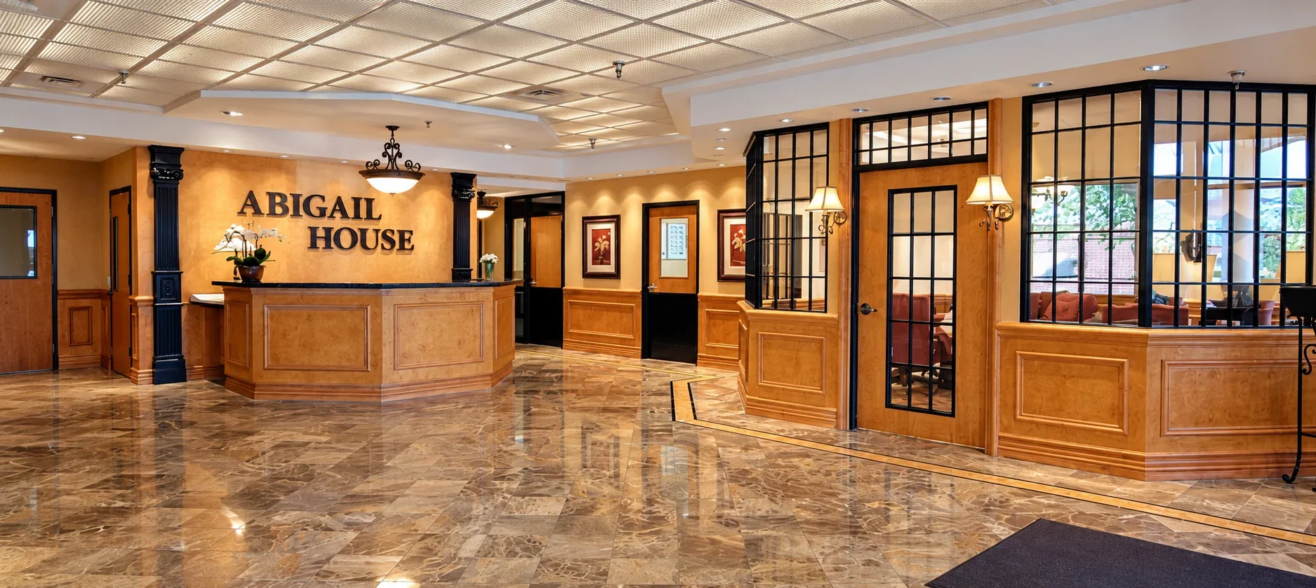 Abigail House: Reception desk with wood paneling, glass partitions, and patterned flooring
