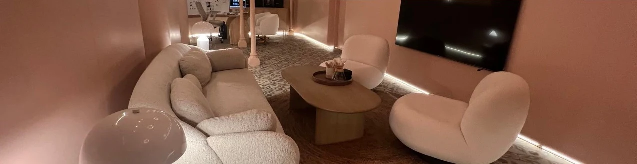 Ansa Coffee: Lounge seating with a cream sofa, rounded chairs and a wall-mounted screen