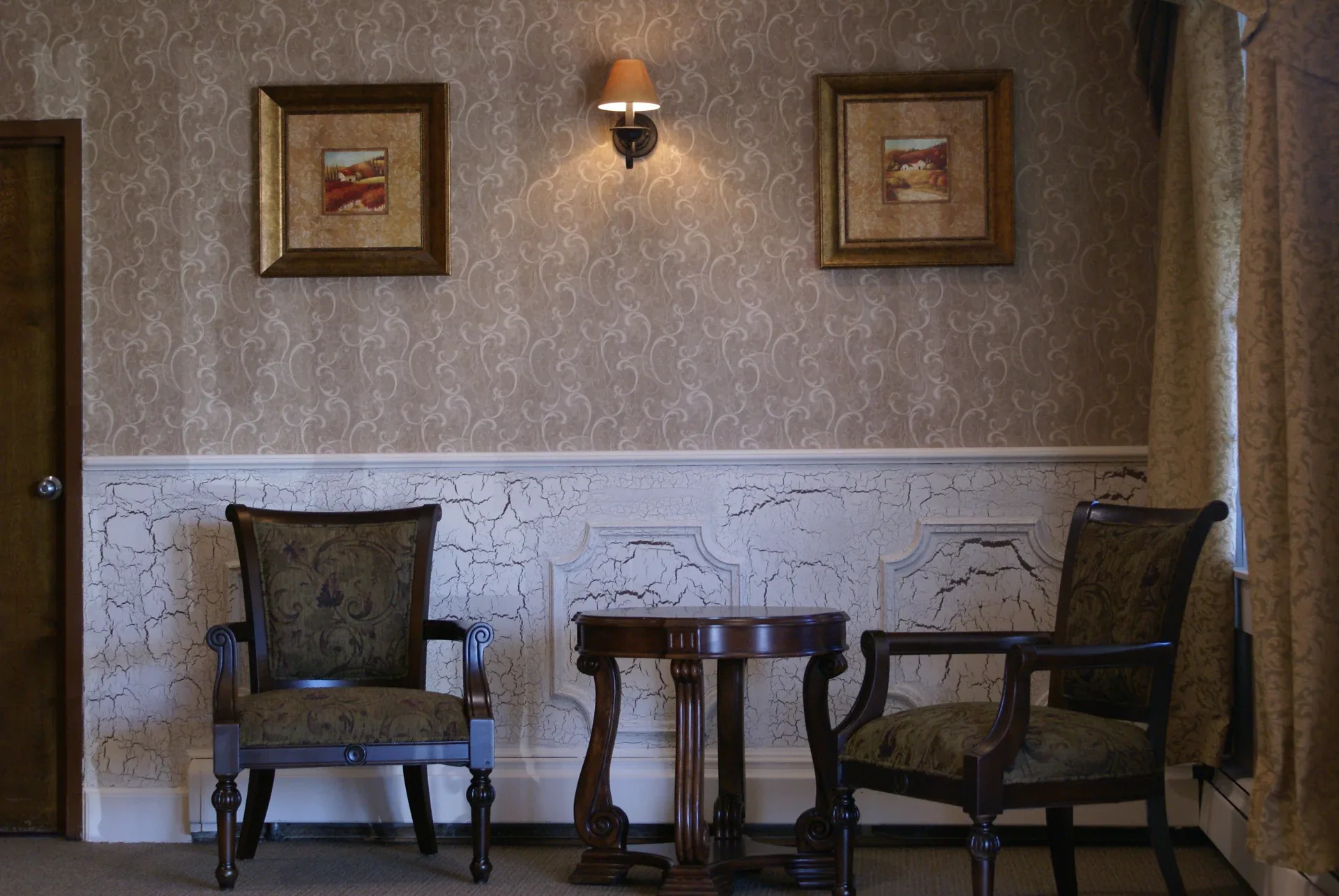 Applegarth: Two upholstered chairs and a round table beneath framed artwork