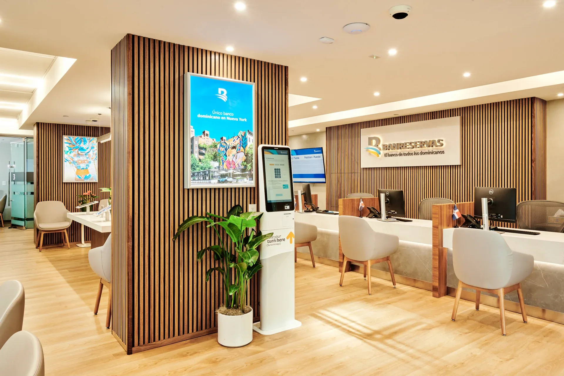 Banreservas: Service counter with wood-slat walls, upholstered chairs and a freestanding digital kiosk