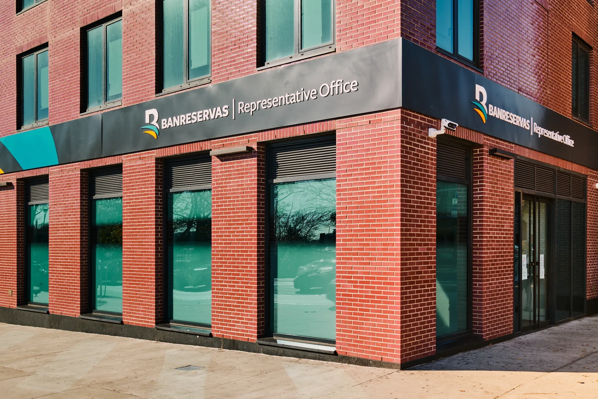 Banreservas: Red-brick corner facade with representative office signage and tall ground-floor windows