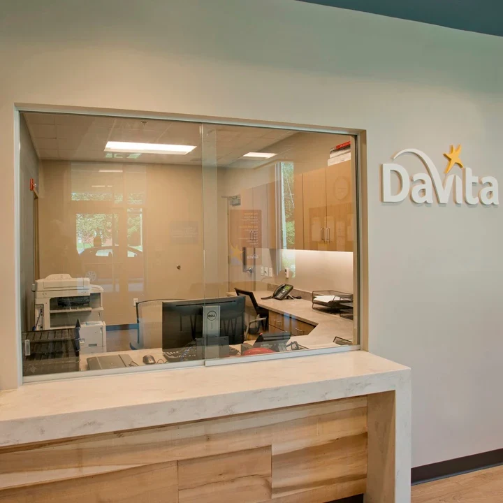 Brooklyn DaVita: Reception window with a wood-paneled counter and DaVita wall sign