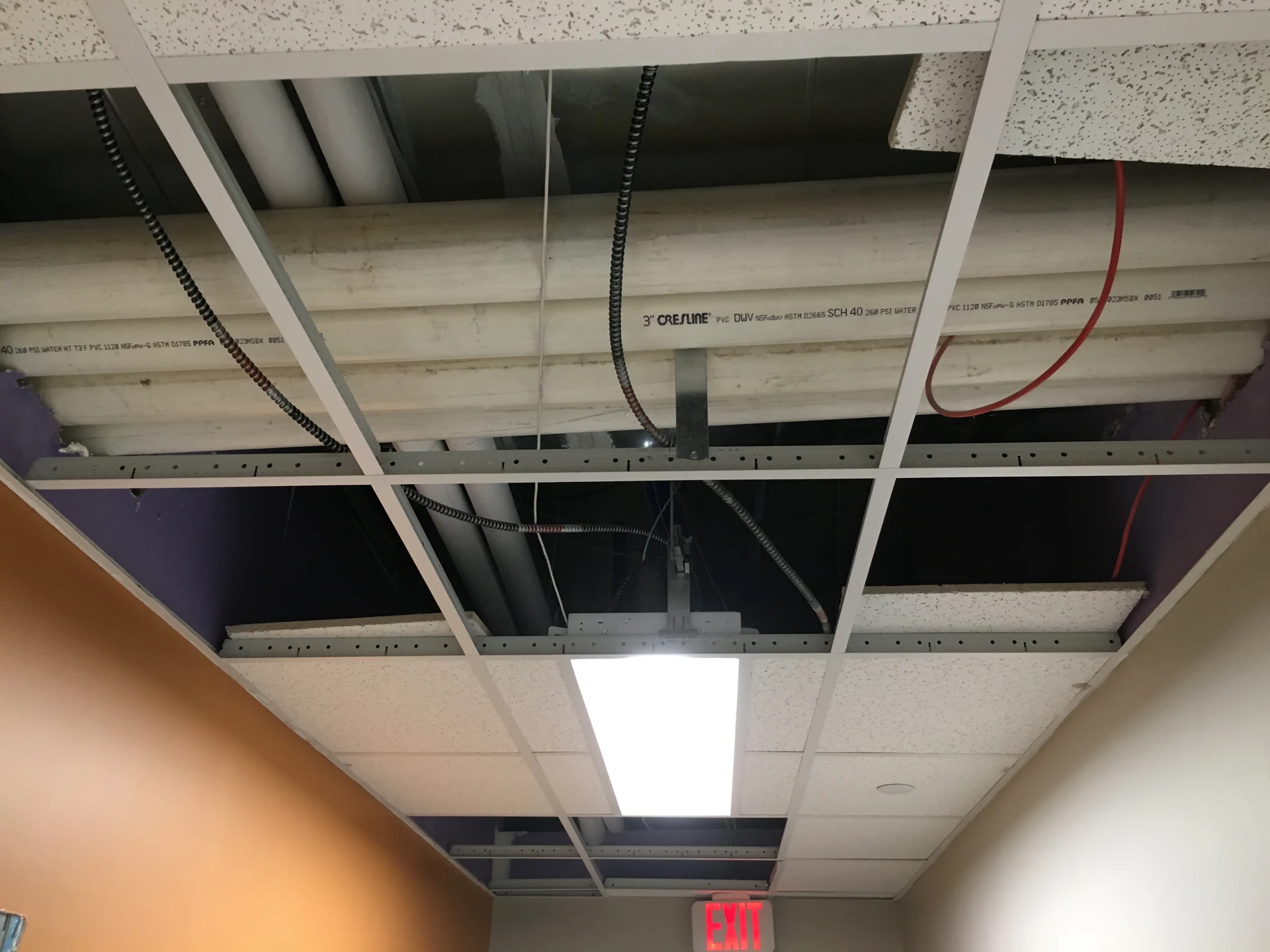 Brooklyn DaVita: Exposed piping and wiring above a partially installed suspended ceiling