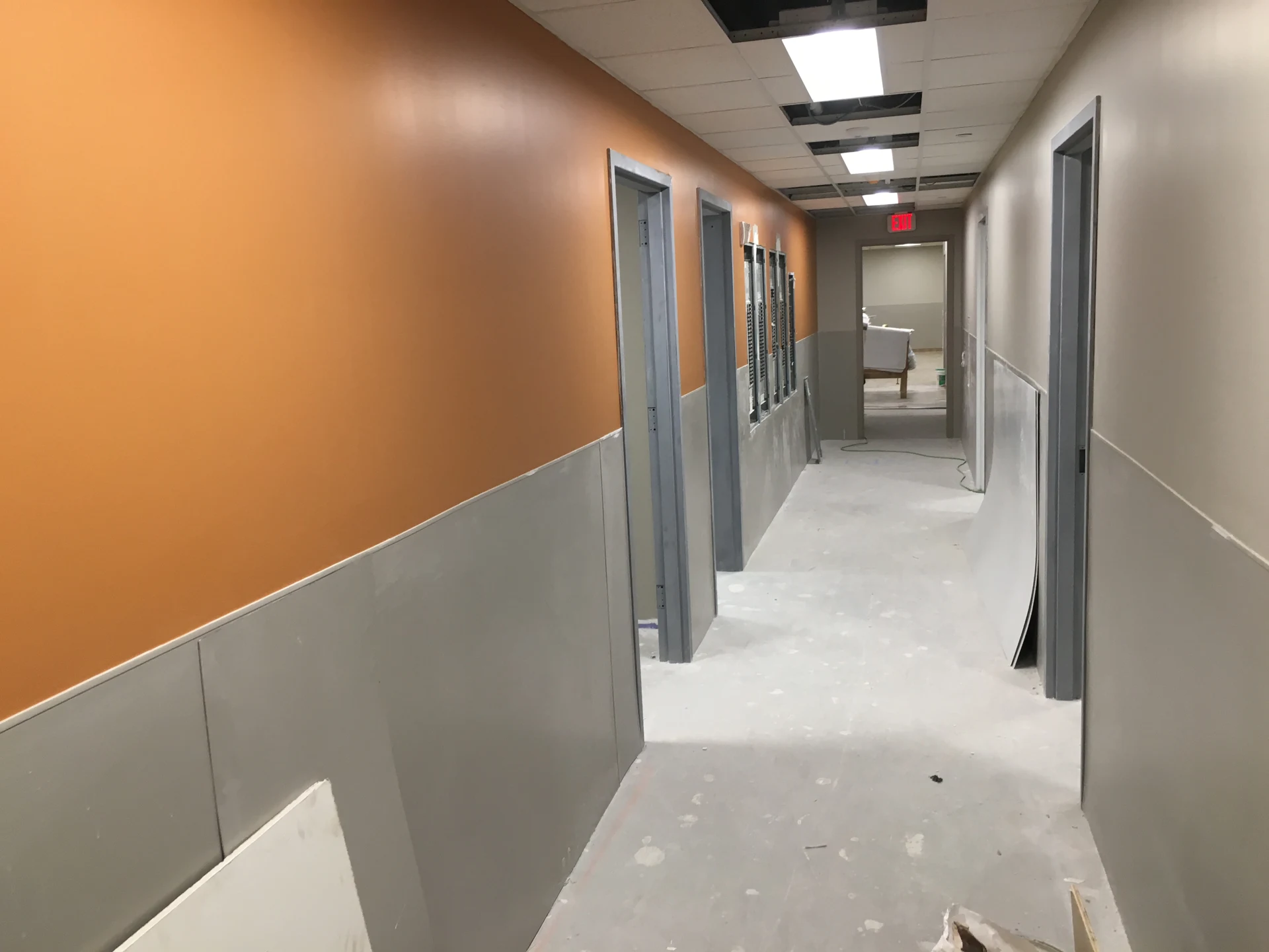 Brooklyn DaVita: Corridor under construction with orange walls and missing ceiling panels