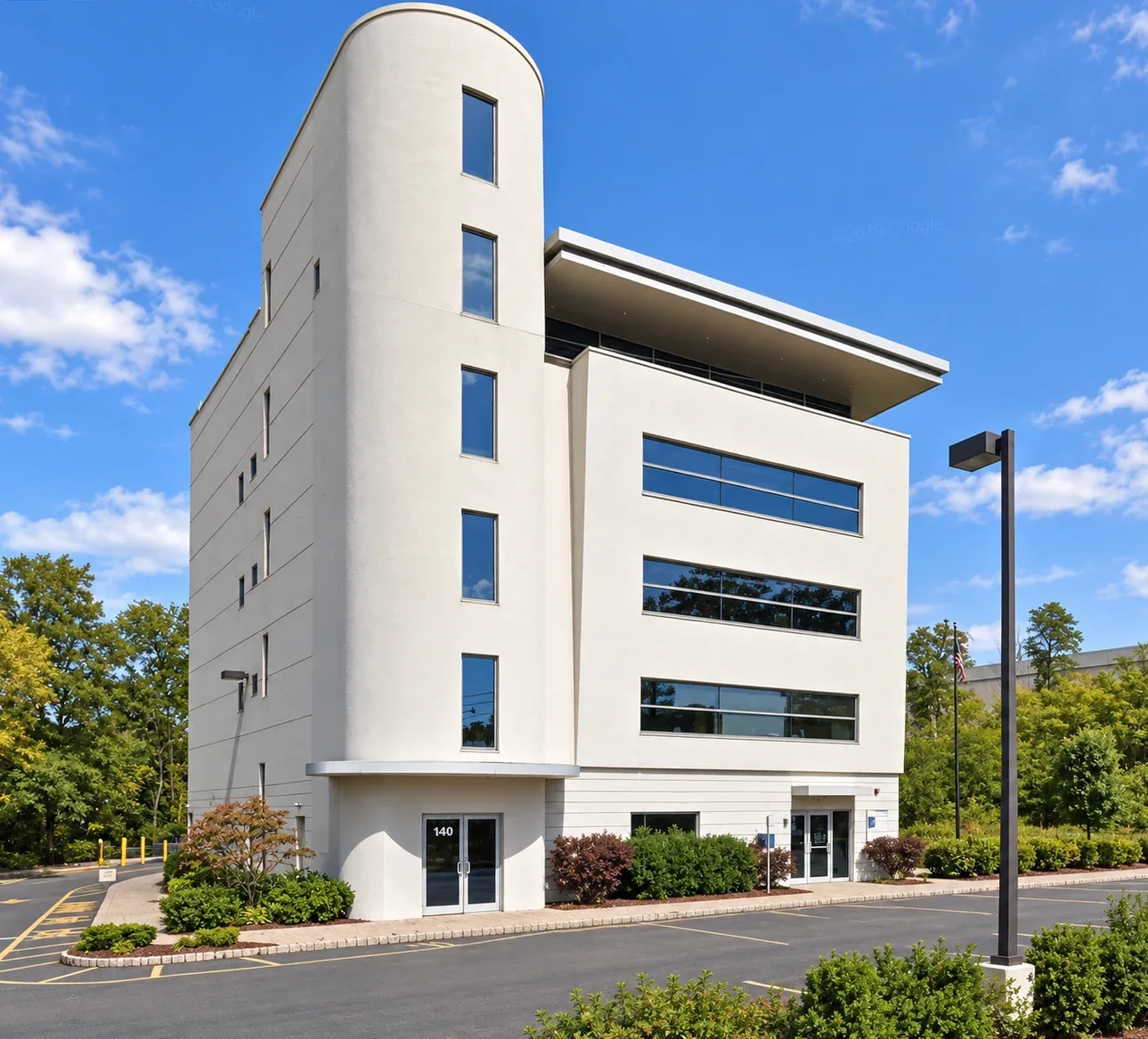 Keasbey: Four-story light-colored building with a rounded corner tower and horizontal windows