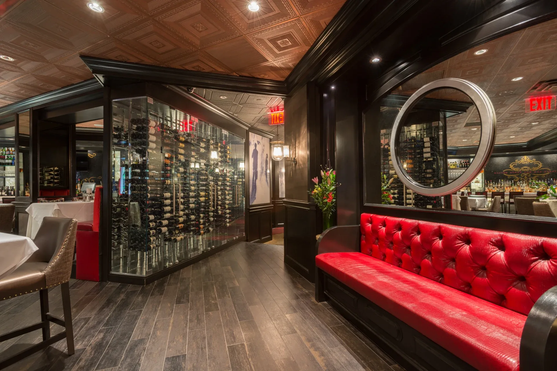 Ruth’s Chris Steakhouse: Glass wine display beside a red tufted bench and circular mirror