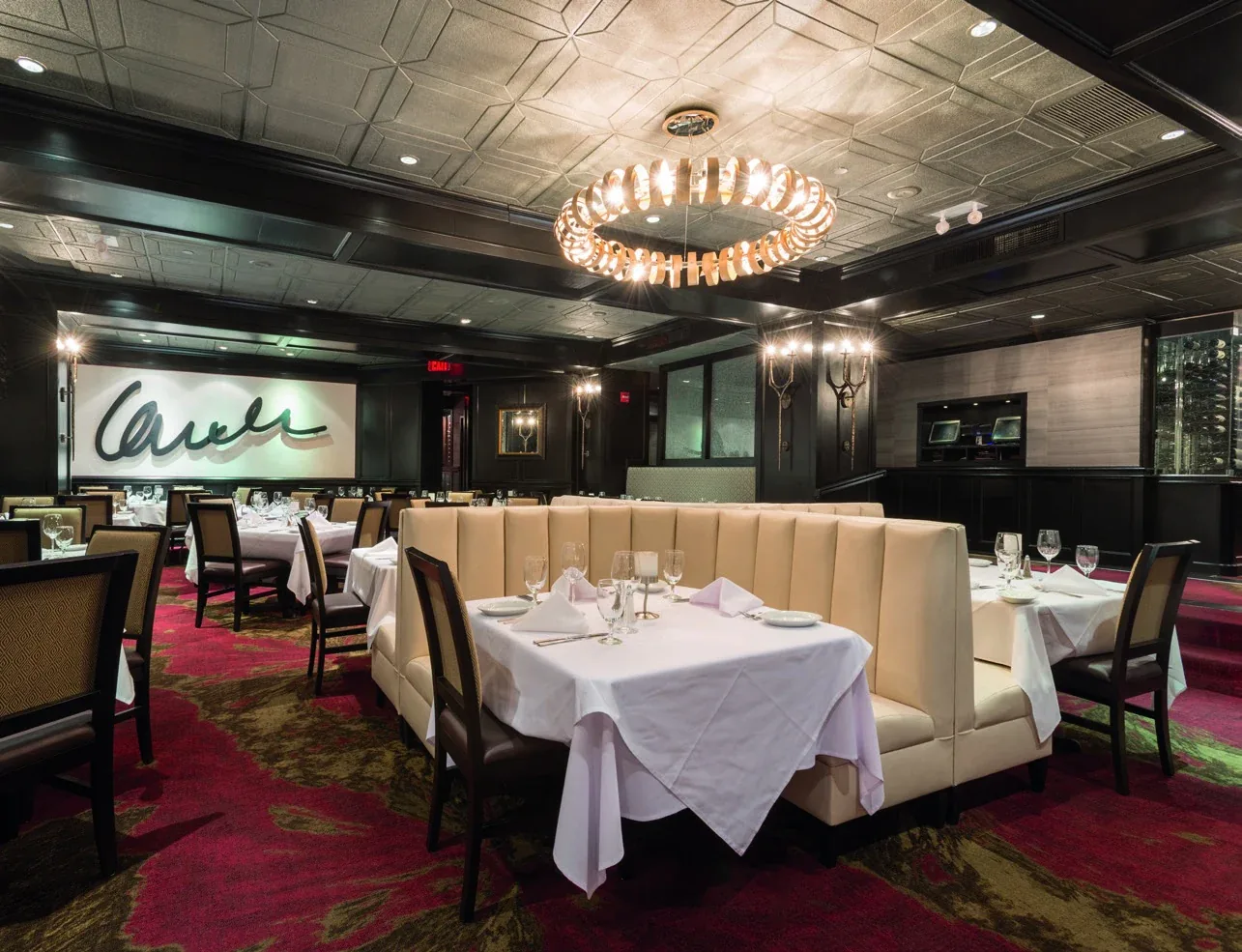 Ruth’s Chris Steakhouse: Dining room with cream booths, white tablecloths and a circular chandelier
