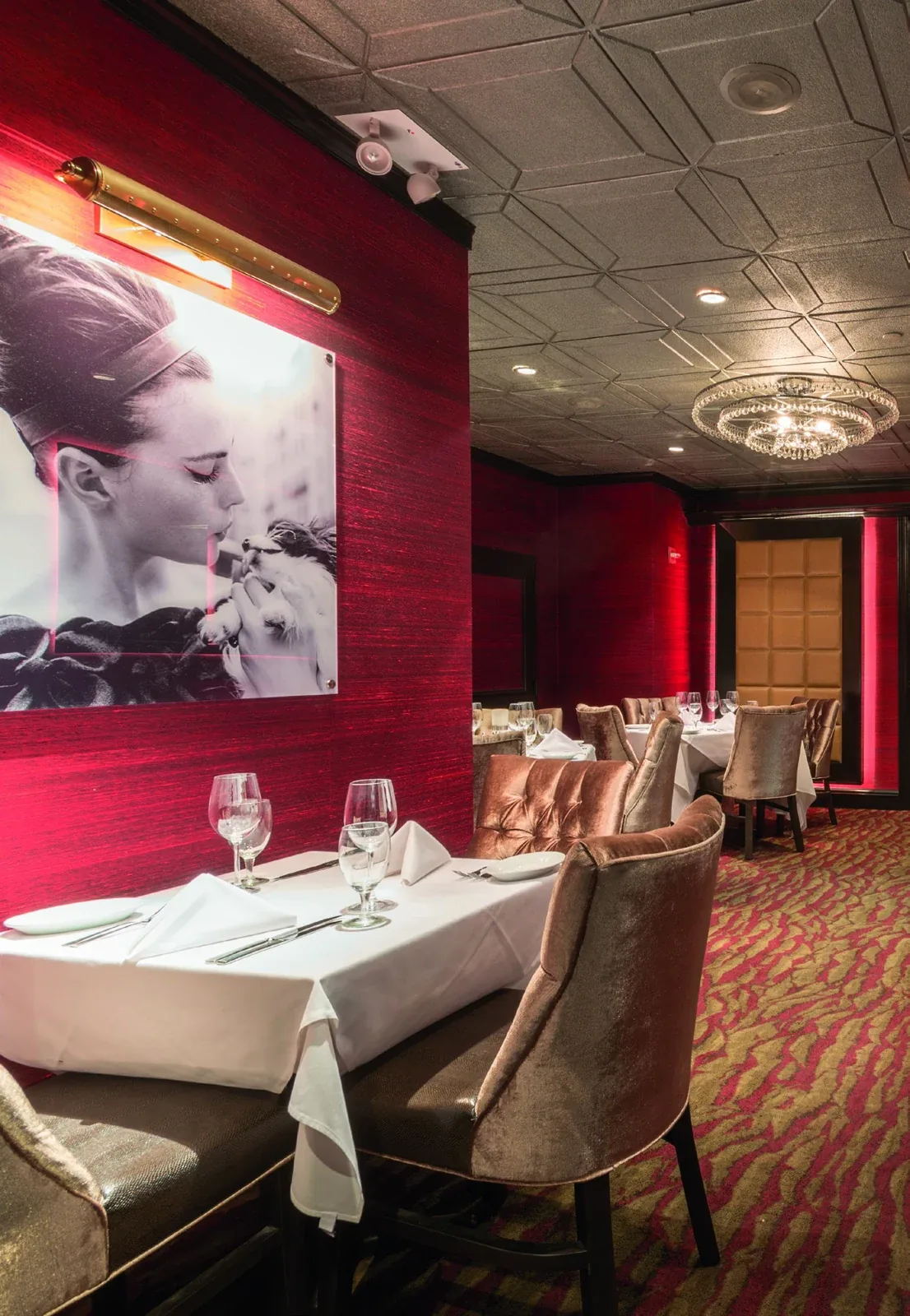 Ruth’s Chris Steakhouse: Dining tables with upholstered chairs, red walls and patterned carpeting