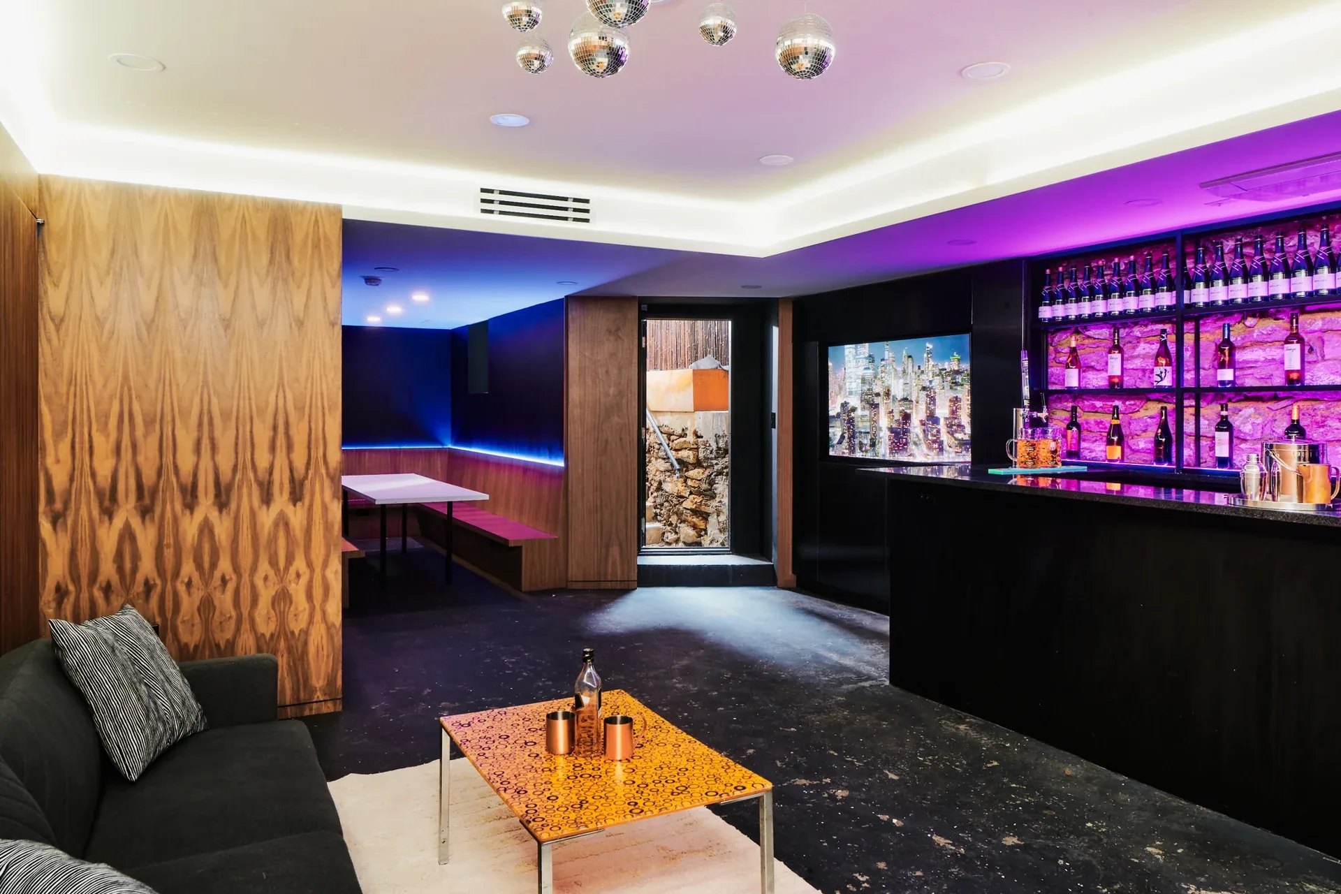 Sigma Nu Fraternity: Bar lounge with illuminated bottle shelves, banquette seating and hanging mirrored balls