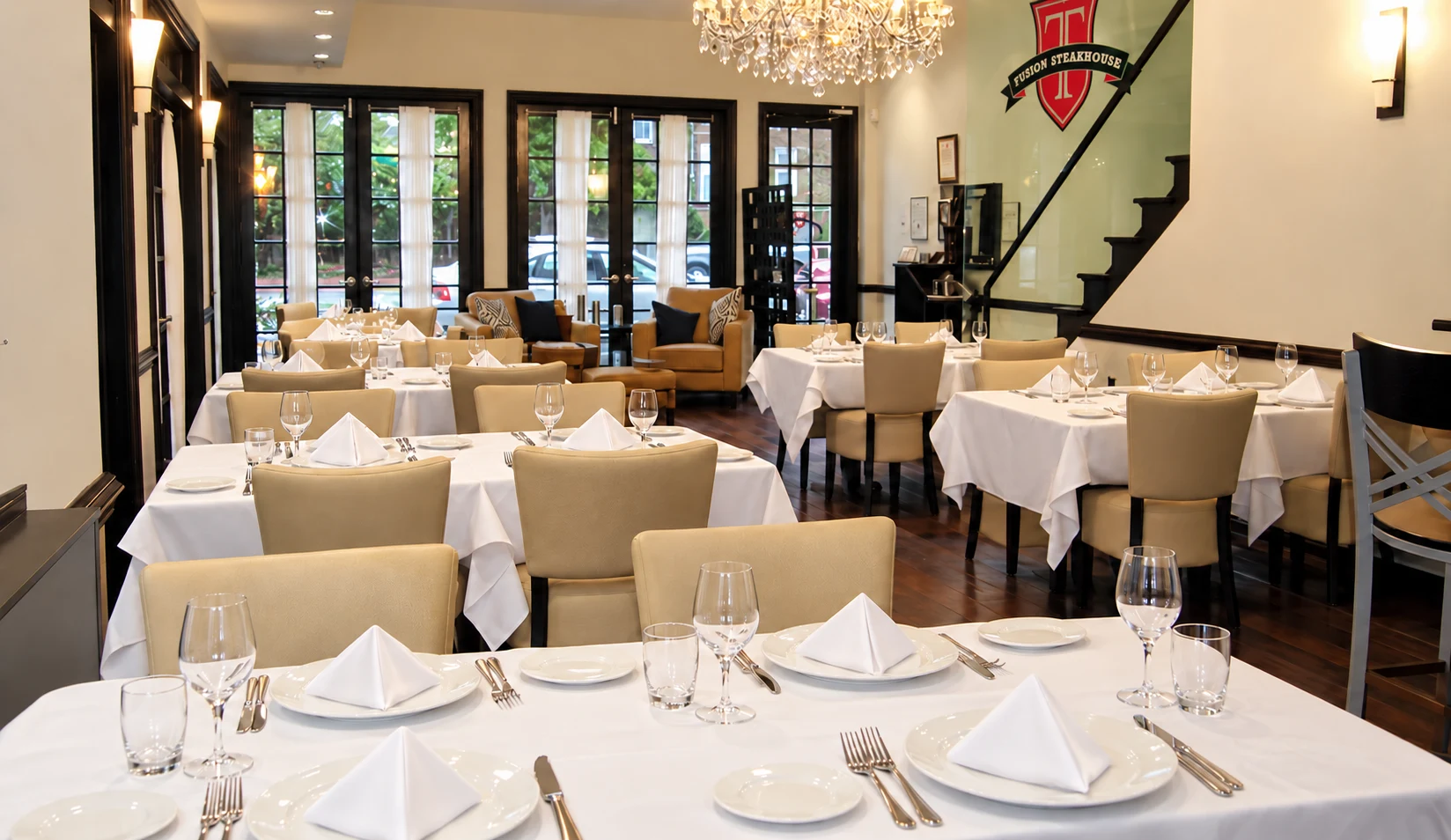 T Fusion Steakhouse: Dining room with cream chairs, white tablecloths and a crystal chandelier