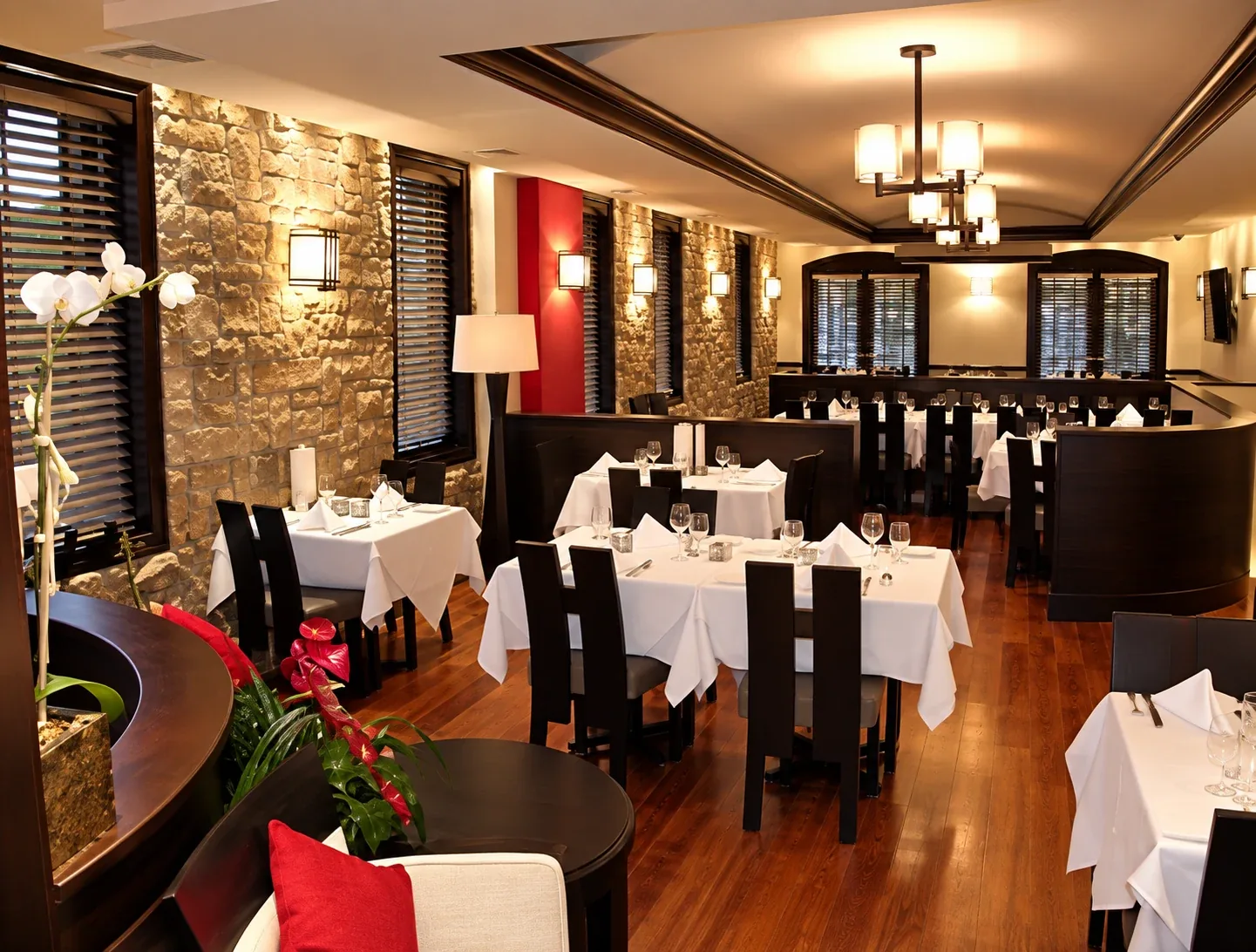 T Fusion Steakhouse: Dining room with stone walls, wood flooring and dark curved partitions