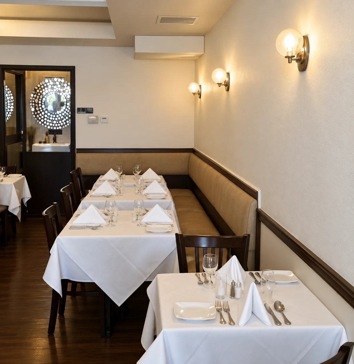 Tea For Two: Banquette seating beside white-clothed dining tables and globe wall lights