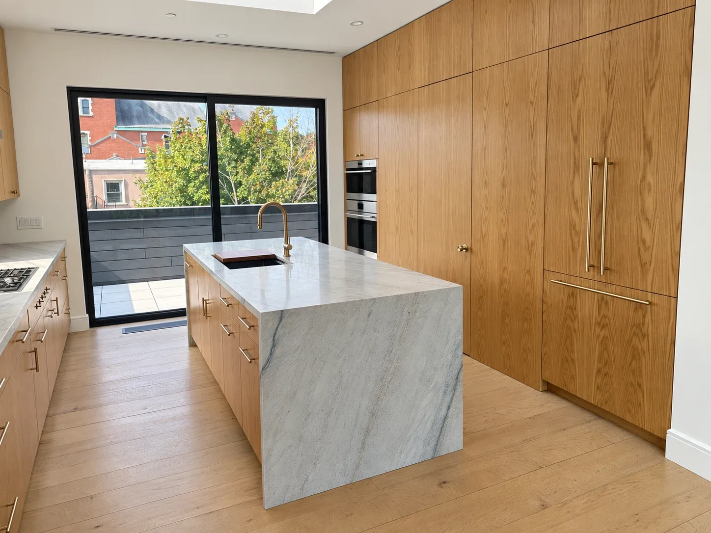 Thump: Kitchen with wood cabinetry, a stone waterfall island and sliding glass doors