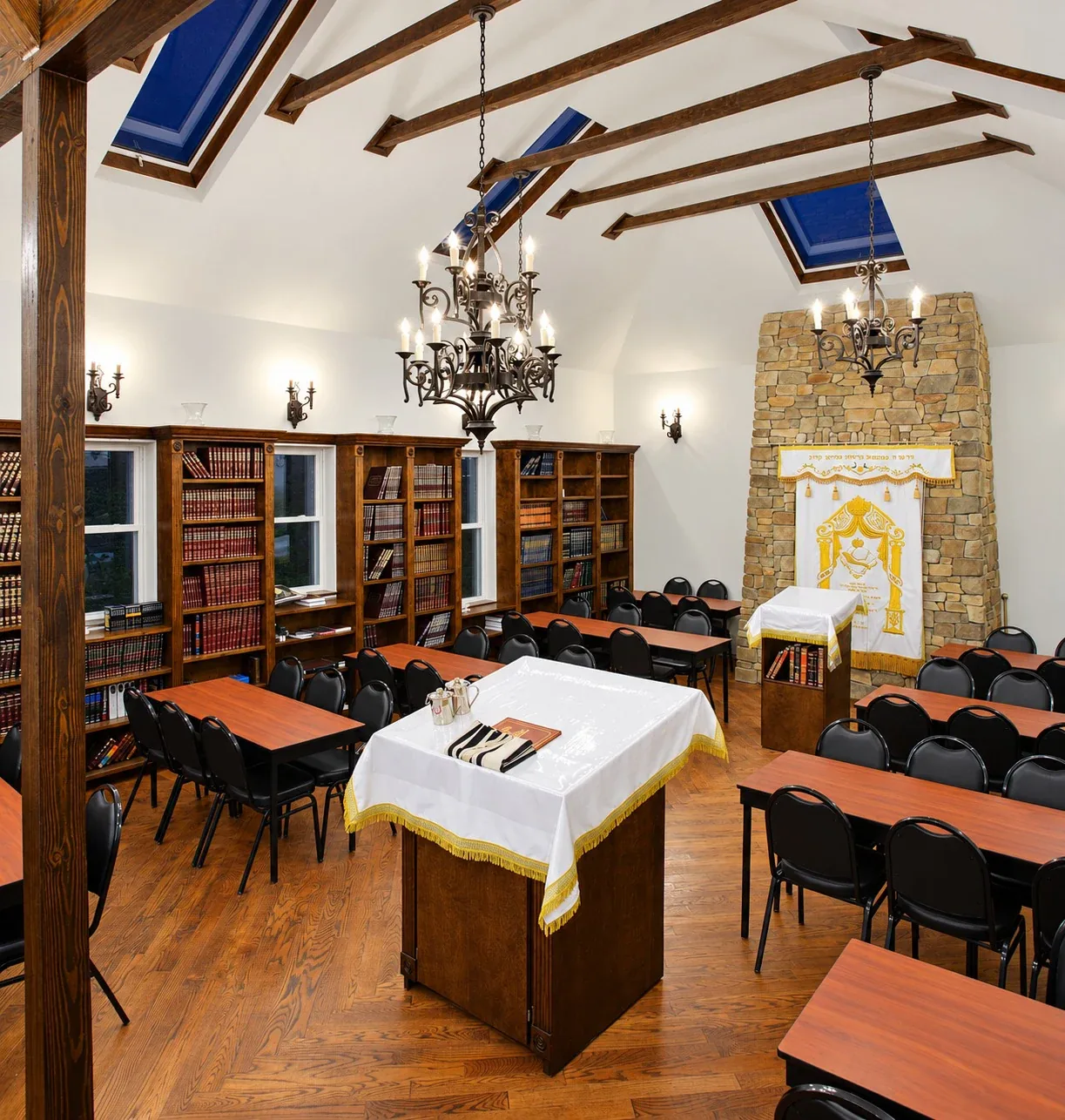 Yeshiva Ateres Shimon: Book-lined hall with chandeliers, wood tables and a stone accent wall